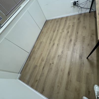 רצפת פרקט בחדר עם קיר לבן ושולחן קטן