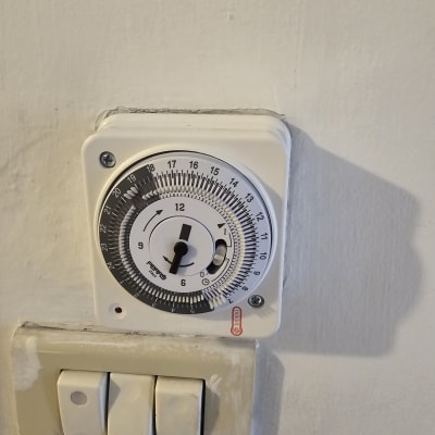 שעון טיימר חשמלי ומתגי תאורה על קיר