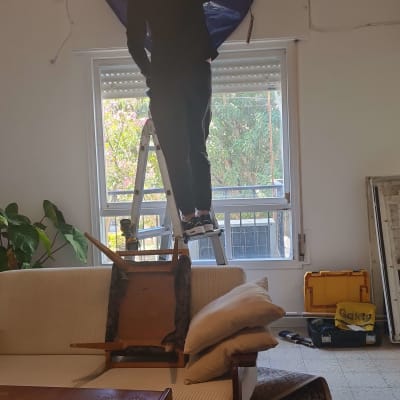 אדם על סולם מתקין מזגן על קיר