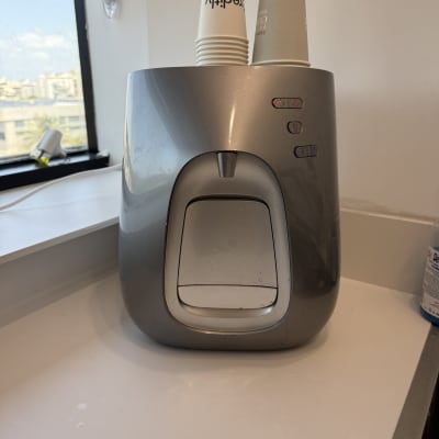 מכונת מים עם כוסות חד פעמיות על השיש