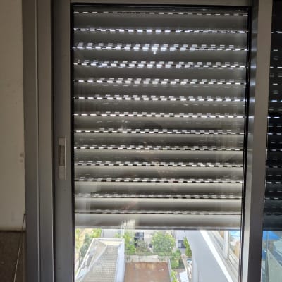 חלון עם תריסים פתוחים למחצה ונוף חיצוני