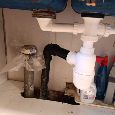 צנרת פלסטיק לבנה מתחת לכיור עם חיבורים