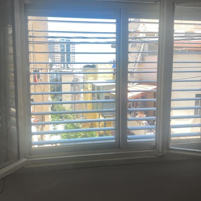 חלון עם תריסי אלומיניום ונוף עירוני ברקע