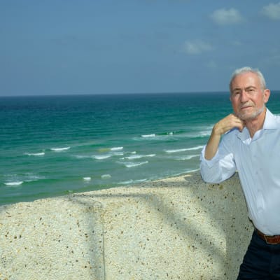 אדם מבוגר עומד ליד חומה מול הים