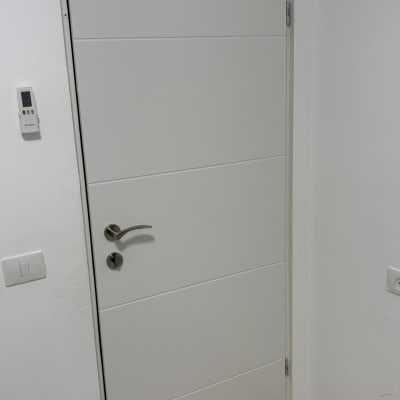 דלת לבנה עם ידית כסופה על קיר לבן