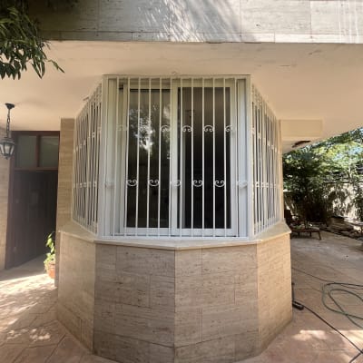 חלון עם סורגים לבנים על קיר אבן חיצוני