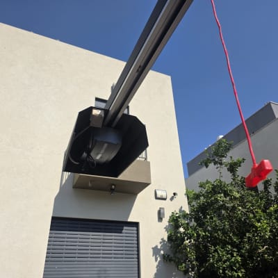 מנוע שער חשמלי עם חוט אדום תלוי ליד בניין