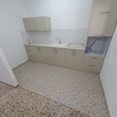 מטבח עם כיור, ארונות וחומר ניקוי על השיש