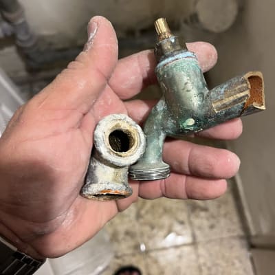 חלקי ברז ישנים עם חלודה ביד של אינסטלטור