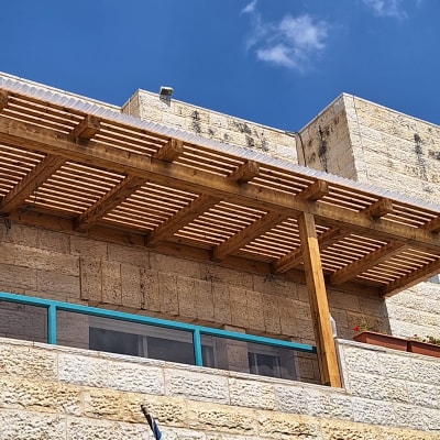 פרגולה מעץ על מרפסת אבן עם עציצים