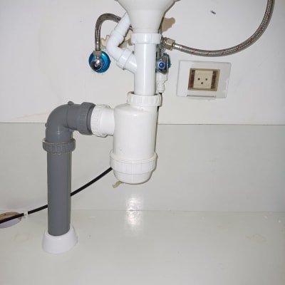 צנרת מתחת לכיור עם ברזים וצינורות