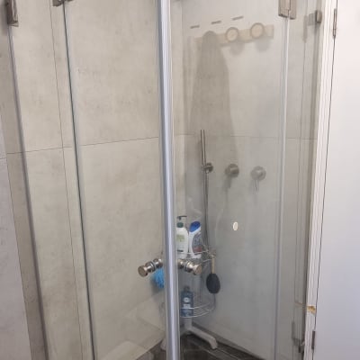 מקלחון זכוכית עם ראש מקלחת ומדף מוצרים