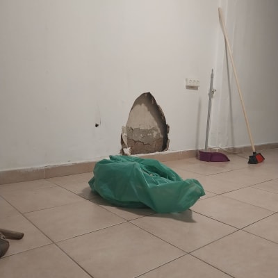 קיר גבס עם חור גדול, מטאטא ויעה בצד