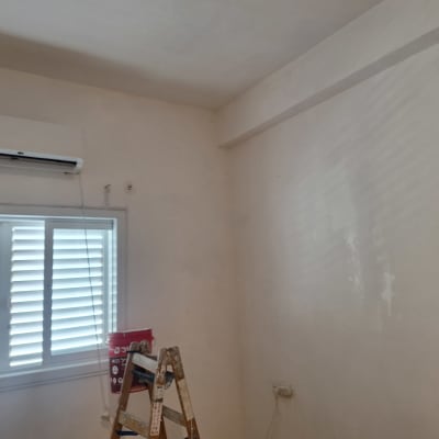 סולם ודלי צבע בחדר עם קיר צבוע