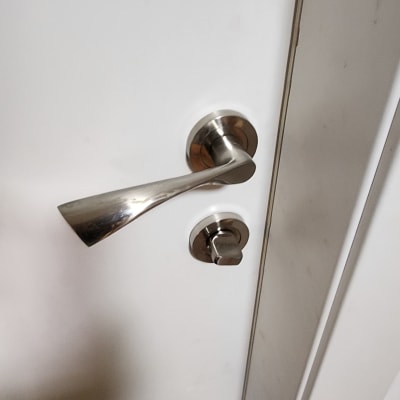 ידית דלת מתכתית על דלת לבנה