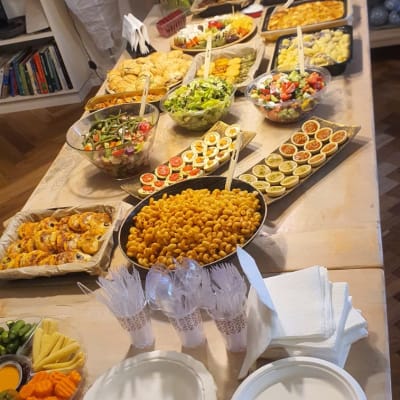 מגוון מנות קייטרינג על שולחן עץ עם סכו"ם חד פעמי