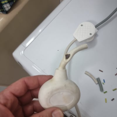 יד מחזיקה כבל חשמל עם תקע לבן וחוטים חשופים