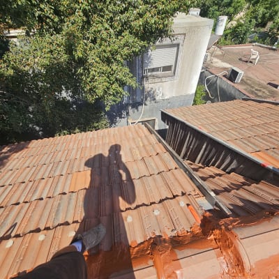 איטום גג עם חומר כתום על רעפים