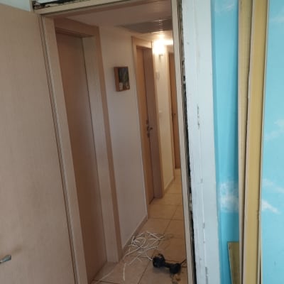 דלת פתוחה עם מסגרת פגומה וכלים על הרצפה