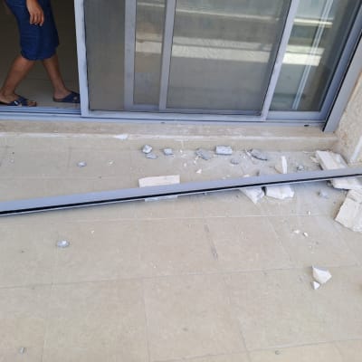 שברי בטון ומוט מתכת על רצפה ליד דלת זכוכית