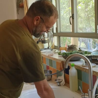 אדם עובד בכיור מטבח עם ברז פתוח