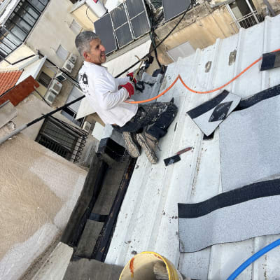 אדם עובד על איטום גג עם יריעות וחומרי איטום