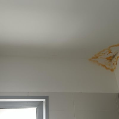 כתם רטיבות על תקרה לבנה בחדר אמבטיה