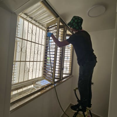 אדם מנקה חלון בעזרת צינור מים