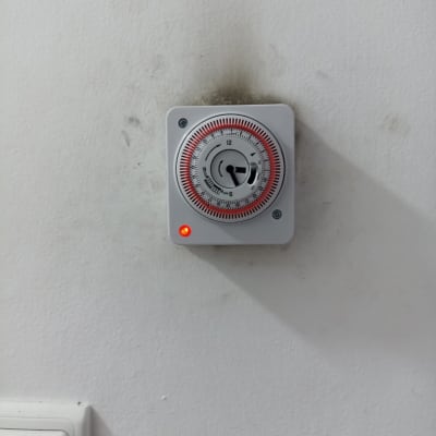 טיימר חשמלי מותקן על קיר עם נורית חיווי דולקת