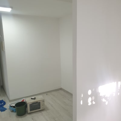 קיר צבוע בלבן עם כתמי אור, דלי ירוק על הרצפה