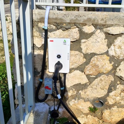 עמדת טעינה חשמלית עם כבל מחובר לקיר אבן