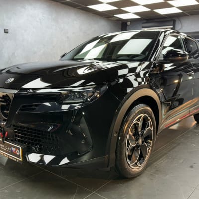 רכב שחור מבריק בחדר תצוגה עם תאורה חזקה