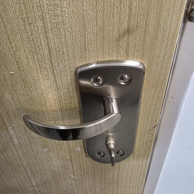 ידית דלת מתכתית על דלת עץ