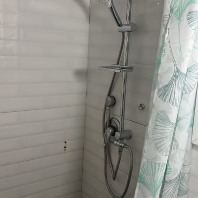 מקלחת עם ראשי מקלחת מותקנים על קיר אריחים לבנים