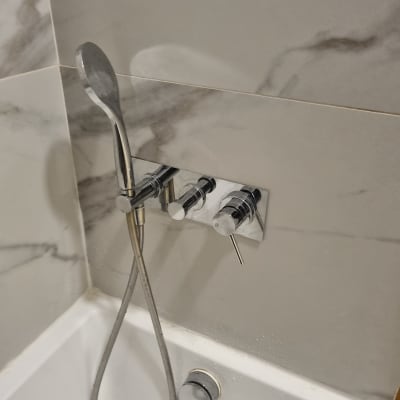 ברז מקלחת עם ידית וכפתורים על קיר שיש