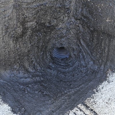 חומר איטום שחור סביב צינור על גג