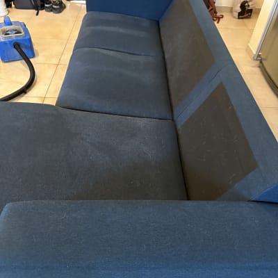 ספה כחולה עם סימני ניקוי וכלי ניקוי בצד