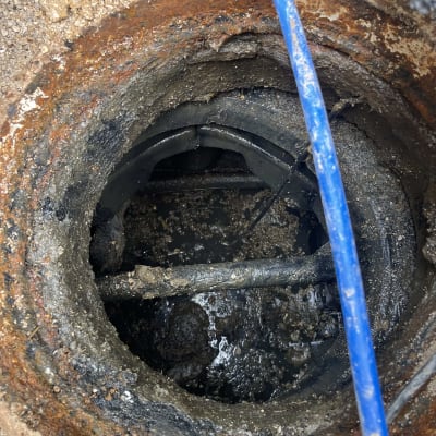 צינור כחול בתוך פתח ביוב חלוד