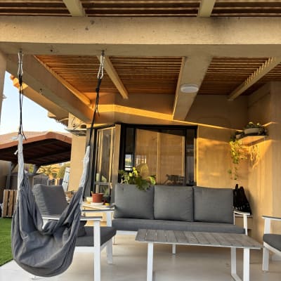 פרגולה מעץ עם כיסא תלוי בגינה