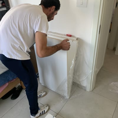 אדם מרכיב רהיט עם מברג אדום