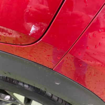 חלק אחורי של רכב אדום עם טיפות מים