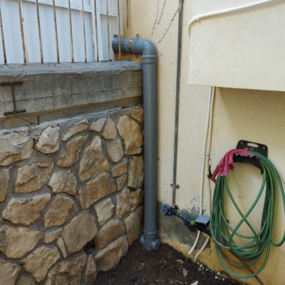 צינור פלסטיק אפור מחובר לקיר עם צינור מים ירוק