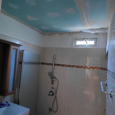 תקרת גבס עם חורים וחוטי חשמל בחדר אמבטיה