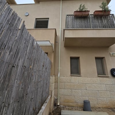 מרזב מחובר לגג בניין עם צמחייה על המרפסת