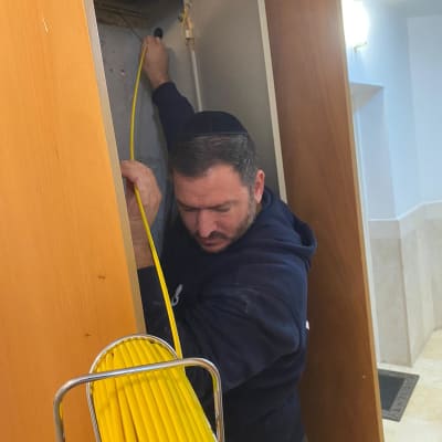 אדם מושך כבל צהוב מתוך ארון חשמל