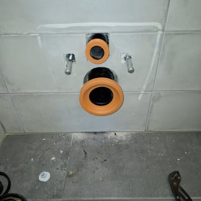 צינור ביוב עם טבעות כתומות על קיר אריחים