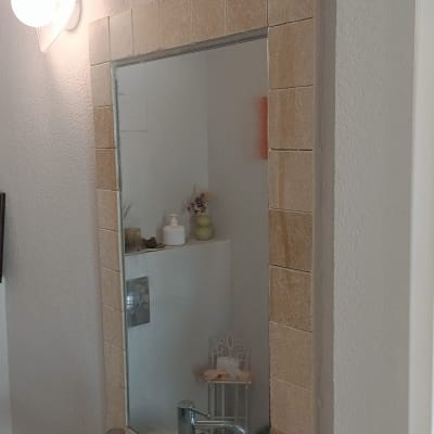 מראה עם מסגרת אריחים וכלי עבודה על כיור