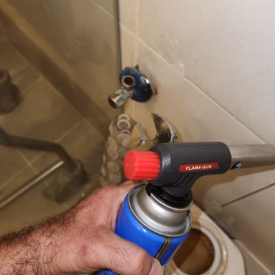 יד מחזיקה מבער גז ליד צינור מים