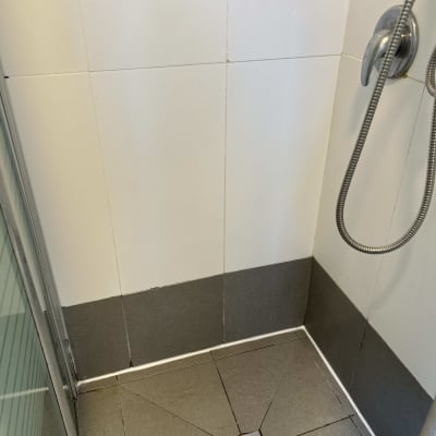 תא מקלחת עם אריחים ומקלחת יד
