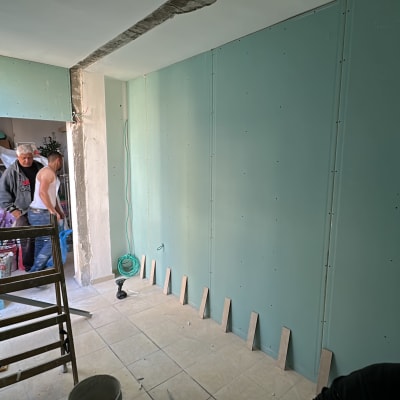 עבודת שיפוץ עם קיר גבס, סולם וכלים.